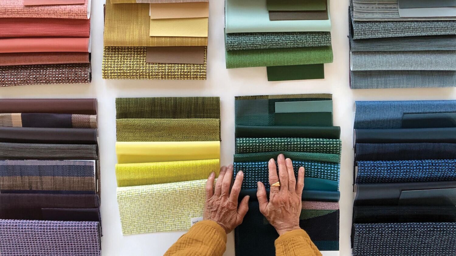 A display of LUUM textiles including different textures, fabrics, and colors like red, orange, purple, yellow, blue, and green